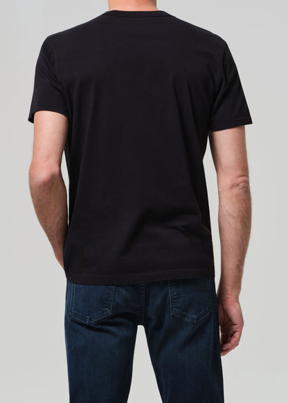 Person wearing a black t-shirt and blue jeans on a plain background