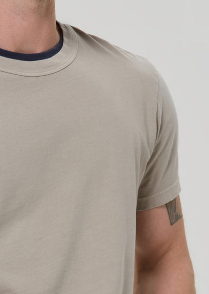 Beige t-shirt worn by a person on a light gray background