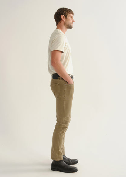 Person wearing ecru short sleeve crewneck t-shirt with tan pants and black boots, side view.