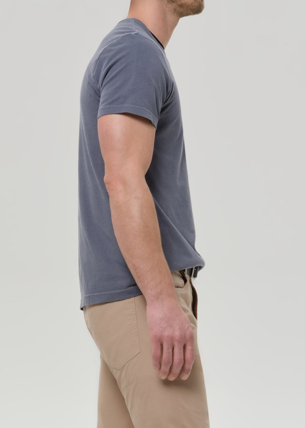 Person wearing a gray t-shirt and beige pants on a plain background