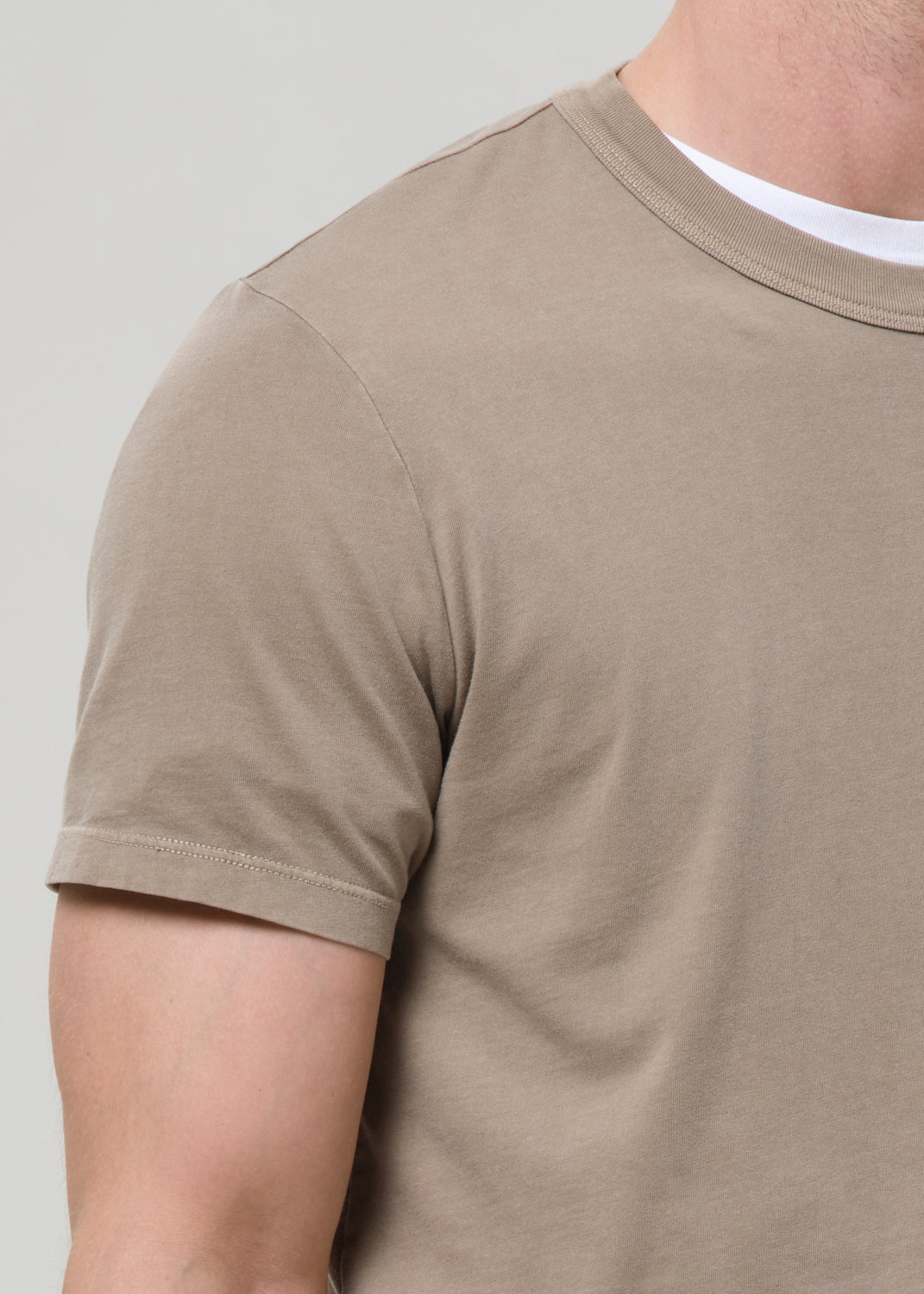 Beige t-shirt worn by a person on a plain background