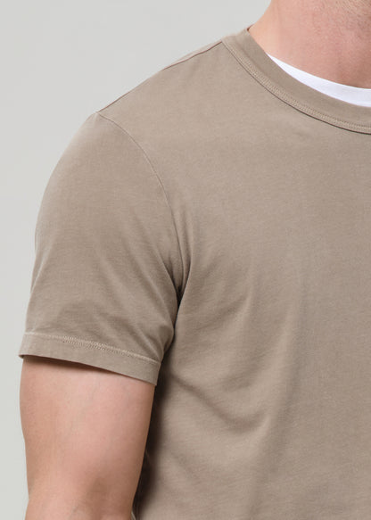 Beige t-shirt worn by a person on a plain background