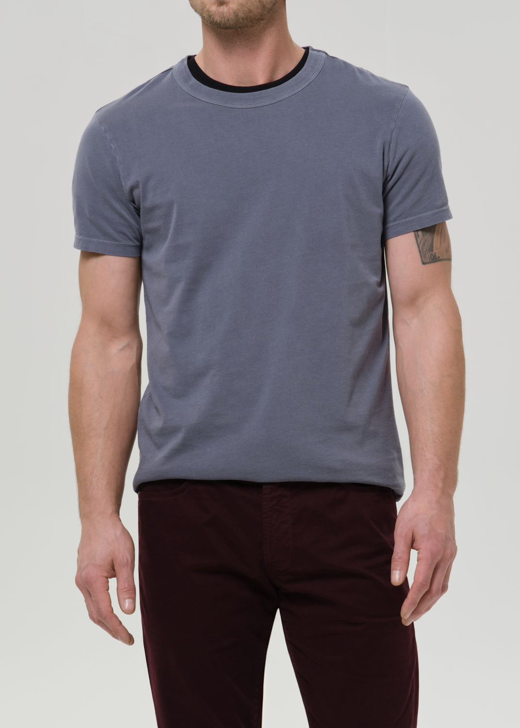 Man wearing a plain gray t-shirt and maroon pants on a light gray background