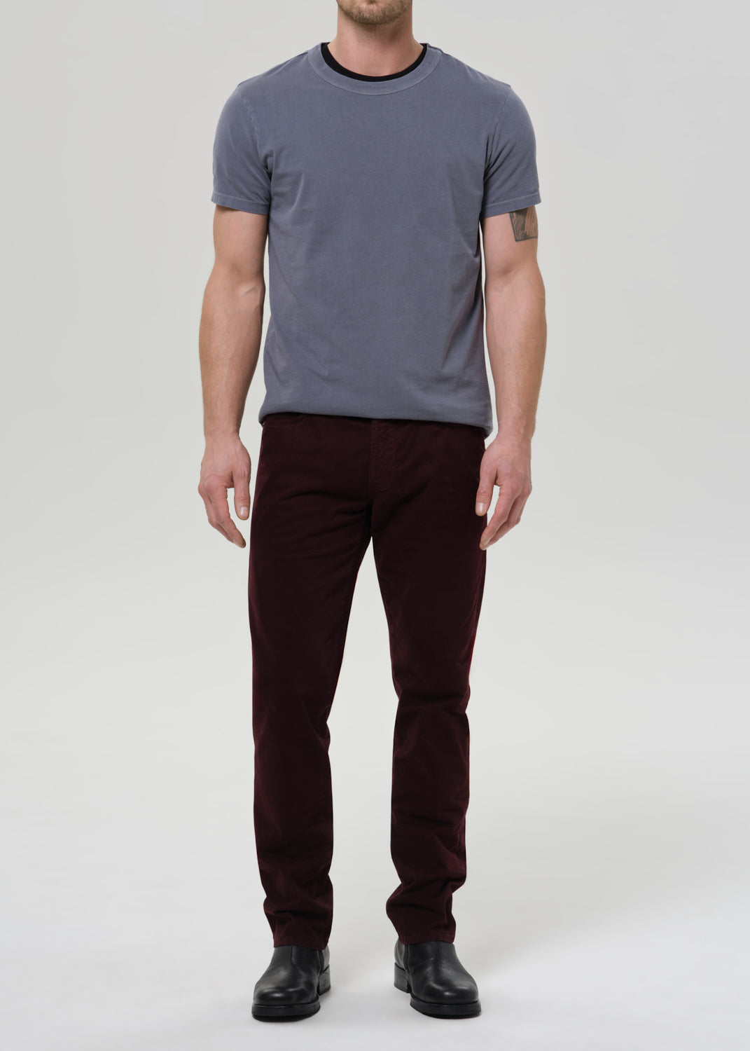 Person wearing a gray t-shirt and dark pants on a white background