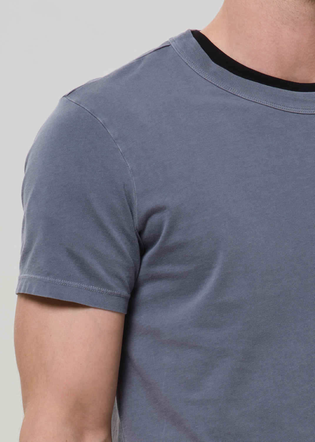 Gray t-shirt worn by a person on a plain background