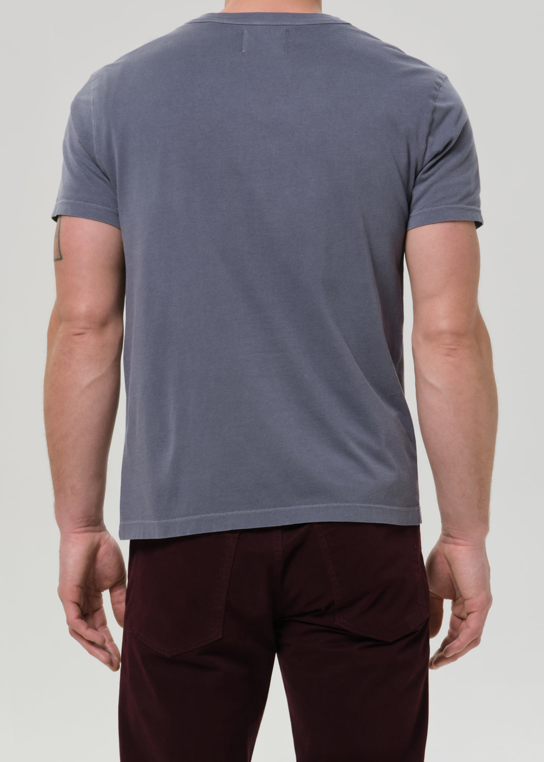 Person wearing a plain gray t-shirt on a light gray background