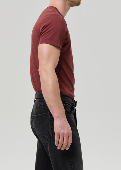 Person wearing a red t-shirt and black pants on a grey background