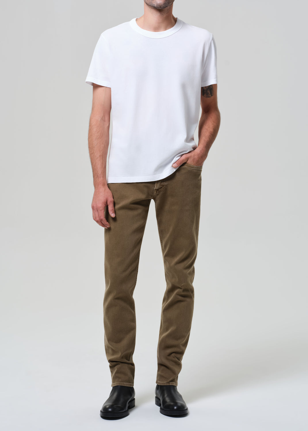Person wearing a white t-shirt and brown pants on a plain background
