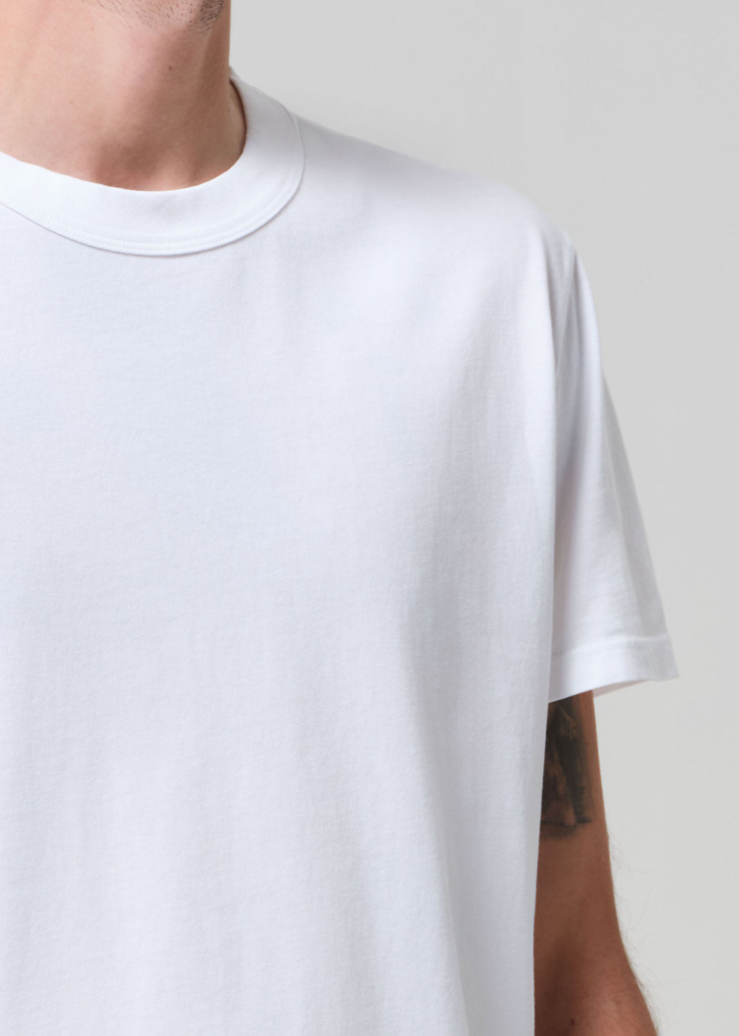 White t-shirt worn by a person on a plain background