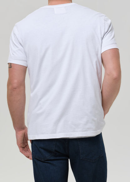 A man viewed from the back wearing a plain white short-sleeve crewneck t-shirt and dark blue jeans, set against a grey background.