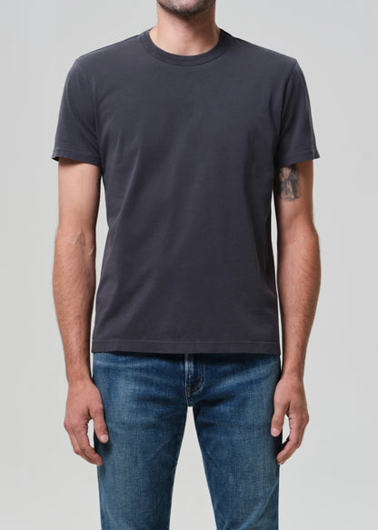 Person wearing a plain grey t-shirt and blue jeans on a light gray background