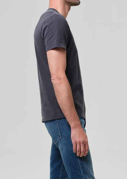 Person wearing a plain grey t-shirt and blue jeans on a light gray background
