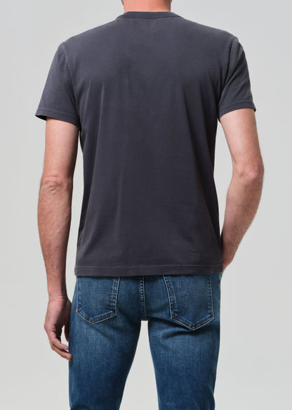 Person wearing a plain grey t-shirt and blue jeans on a light gray background