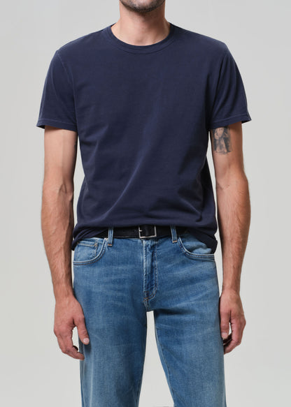 Person wearing a navy blue t-shirt and blue jeans on a plain background