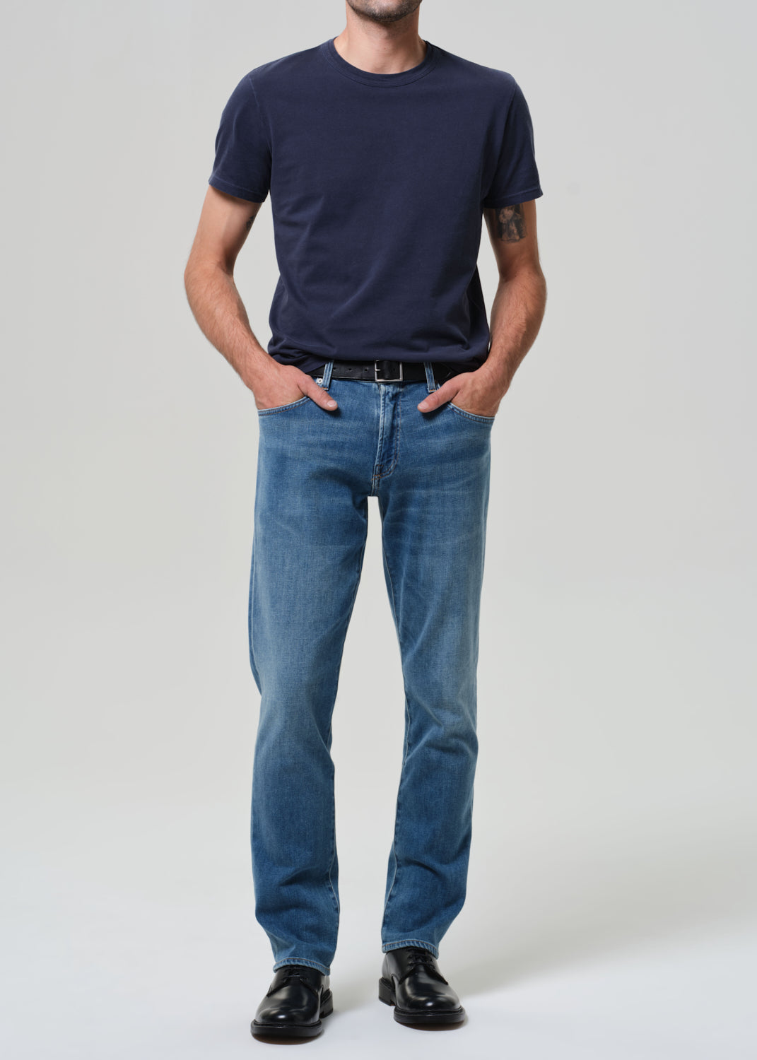 Person wearing a navy t-shirt and blue jeans on a plain background