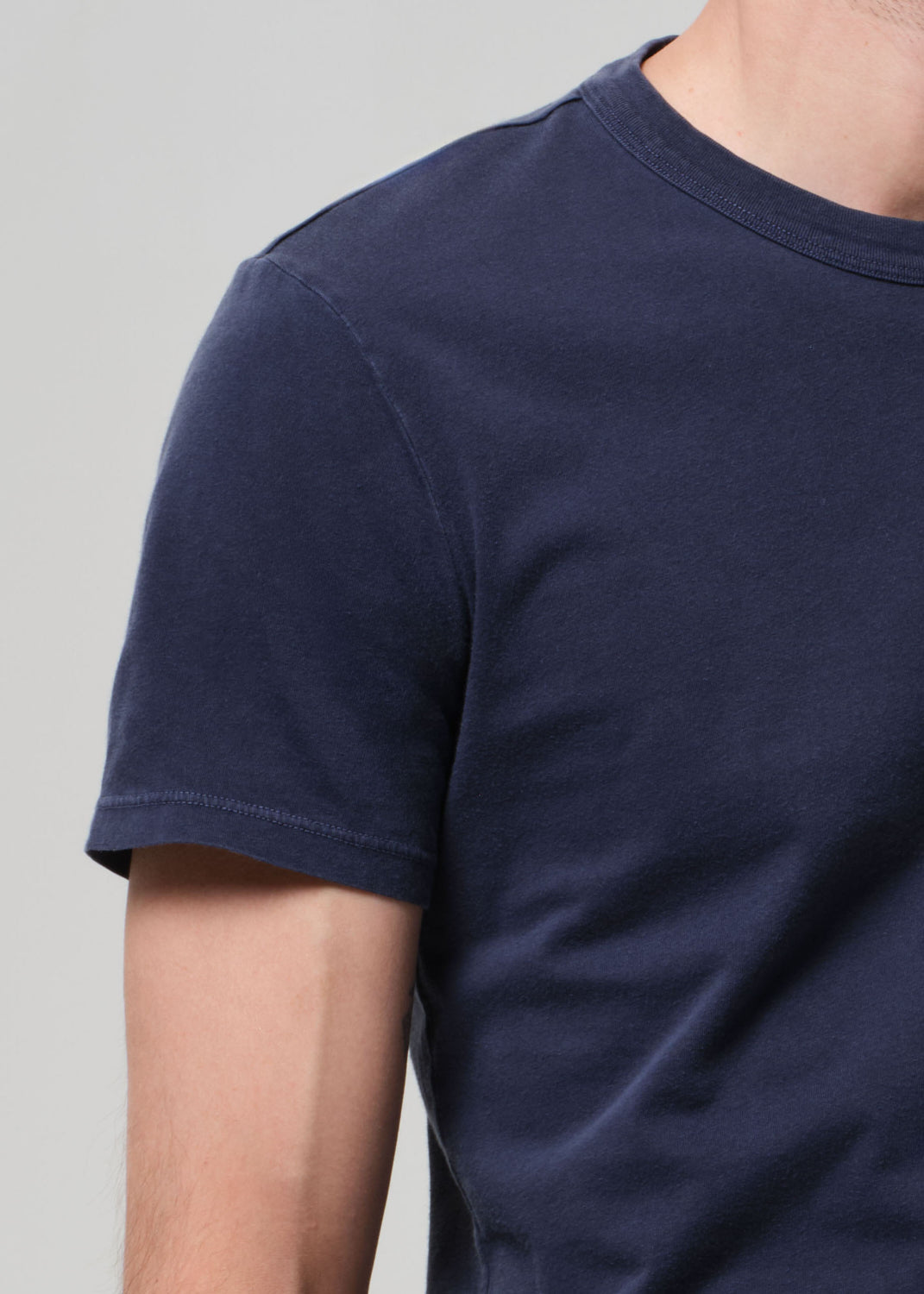 Navy blue t-shirt worn by a person on a light gray background