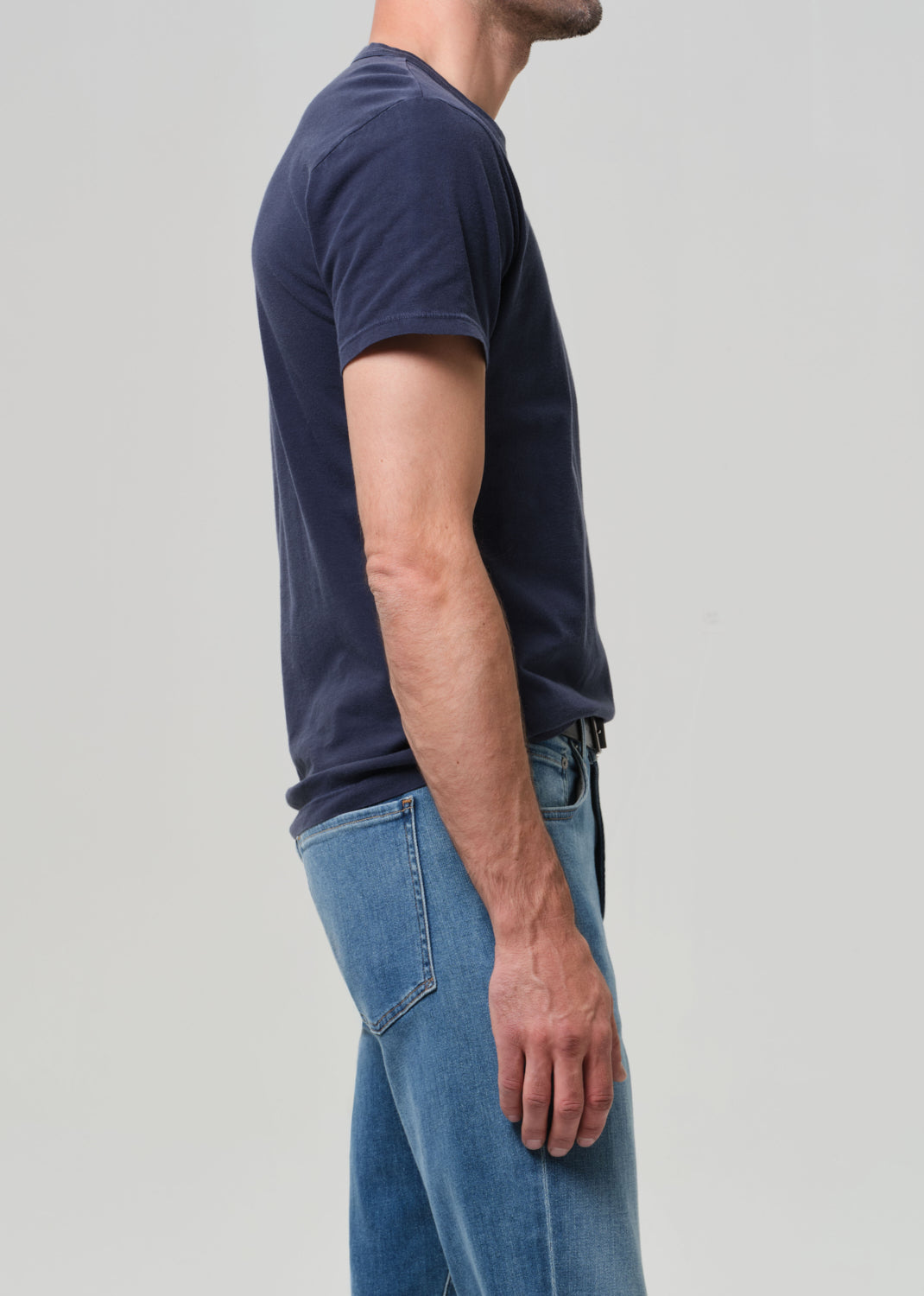 Person wearing a navy t-shirt and blue jeans on a light gray background