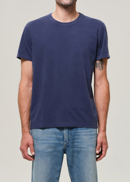 Person wearing a navy blue t-shirt and light blue jeans on a plain background