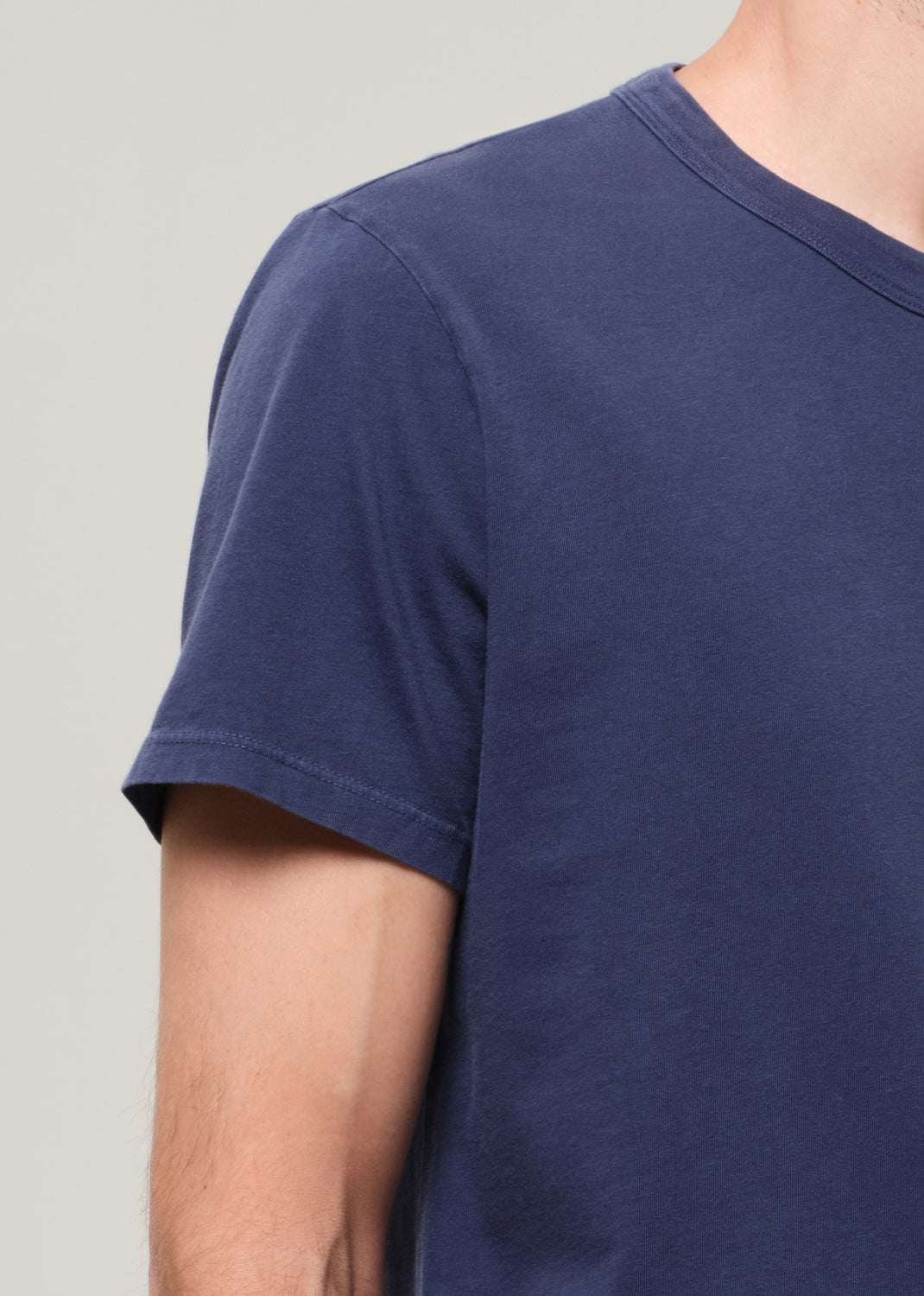 Navy blue t-shirt worn by a person on a plain background