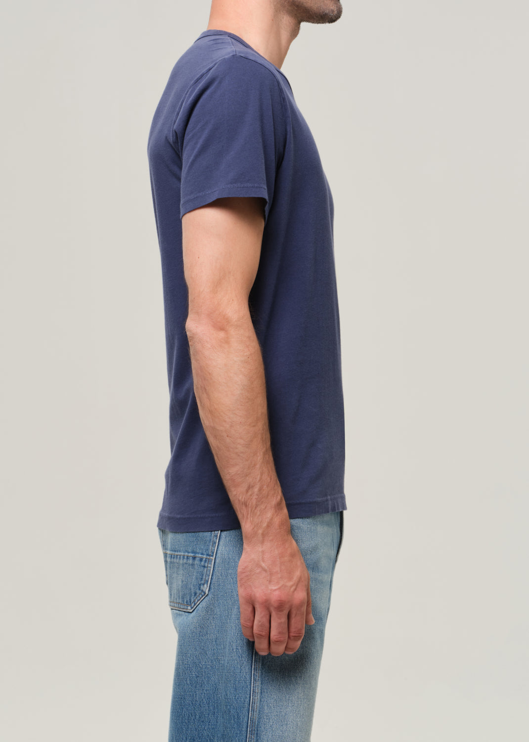 Person wearing a navy blue t-shirt and jeans on a light gray background