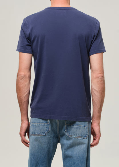 Person wearing a navy blue t-shirt and light blue jeans on a plain background