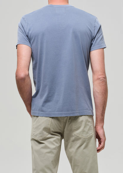 Person wearing a light blue t-shirt and beige pants on a plain background