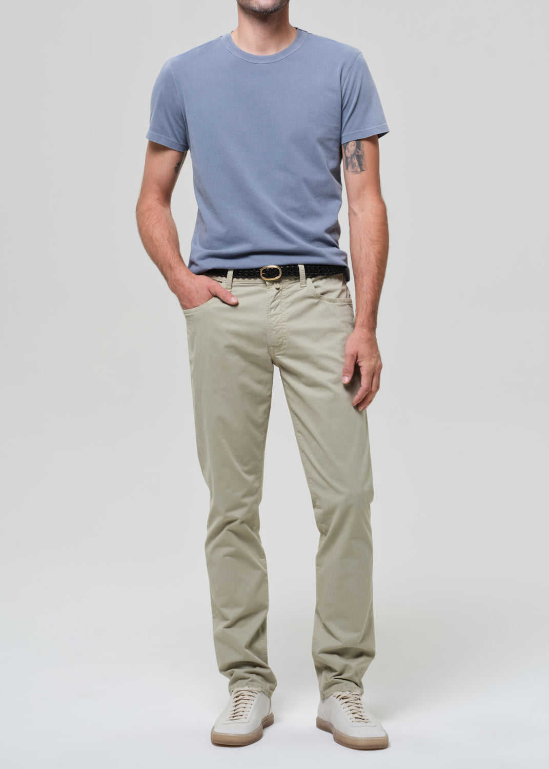 Person wearing a light blue t-shirt and beige pants on a white background
