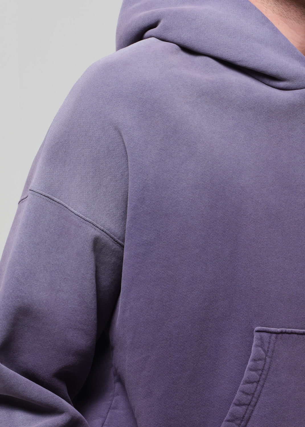 Close-up of a person wearing a purple hoodie with a neutral background