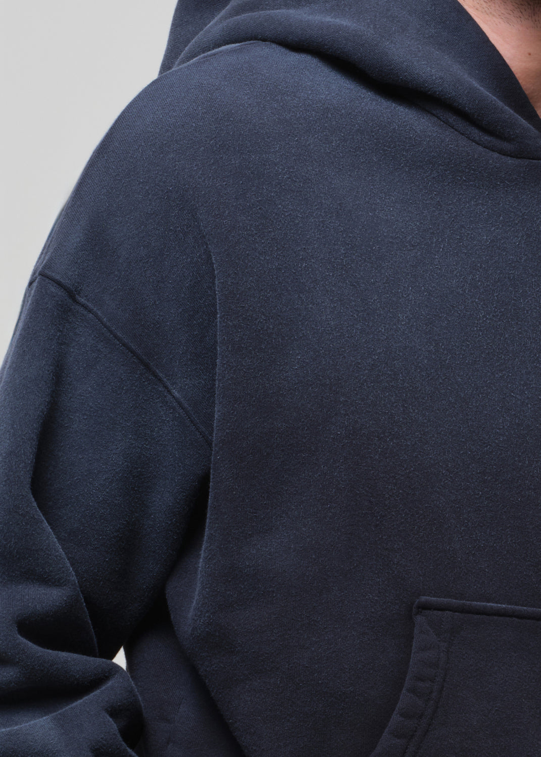 Navy blue hoodie with a pocket on a light gray background