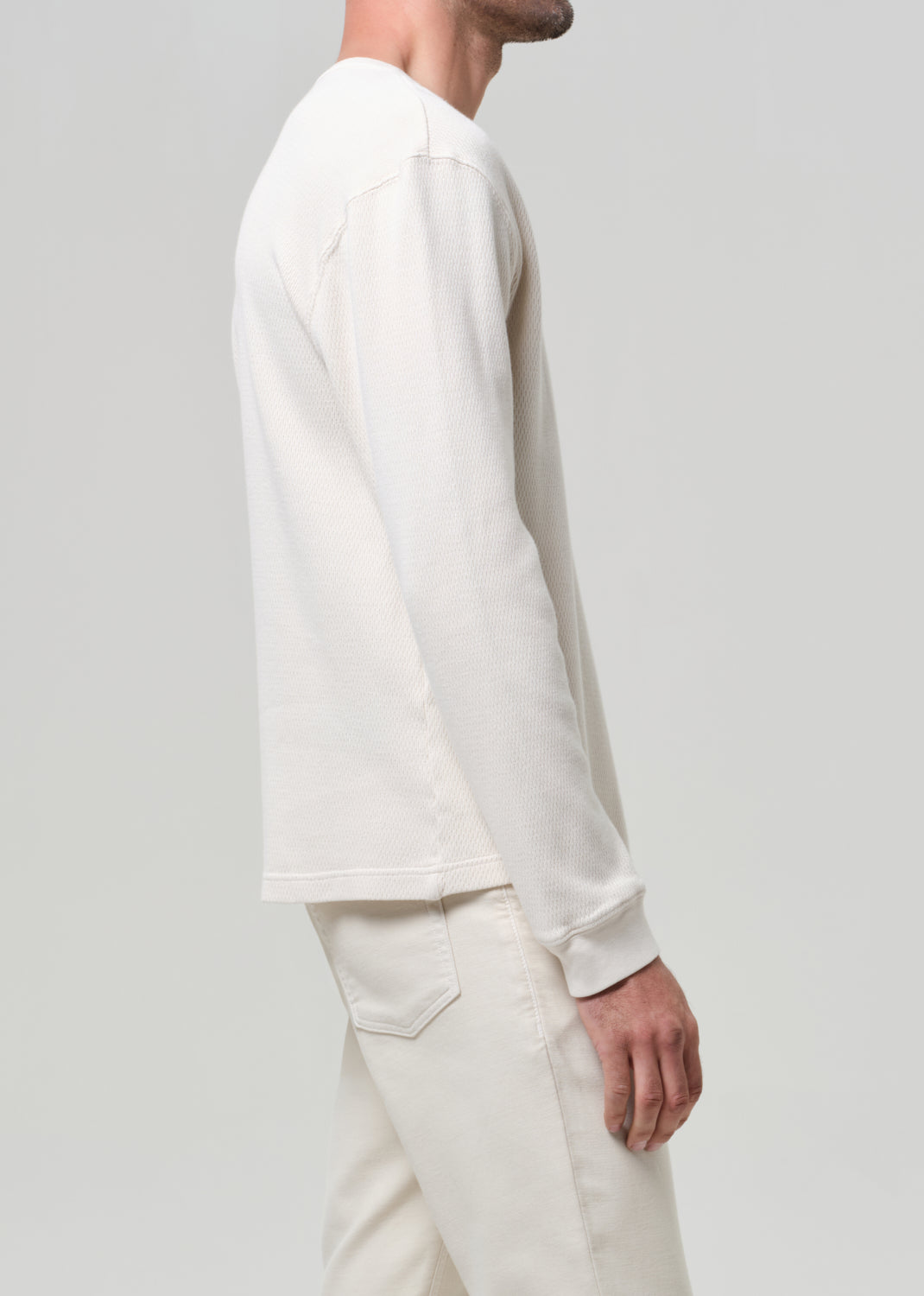 Person wearing a white long-sleeve shirt and pants on a light gray background