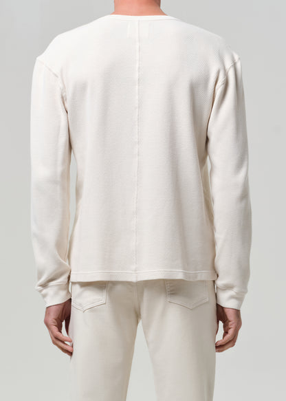 Person wearing a plain white long-sleeve shirt and pants on a light gray background