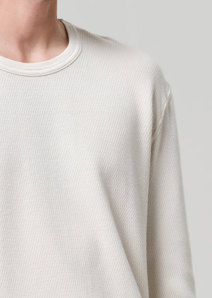 Close-up of a person wearing a textured beige sweater against a plain background