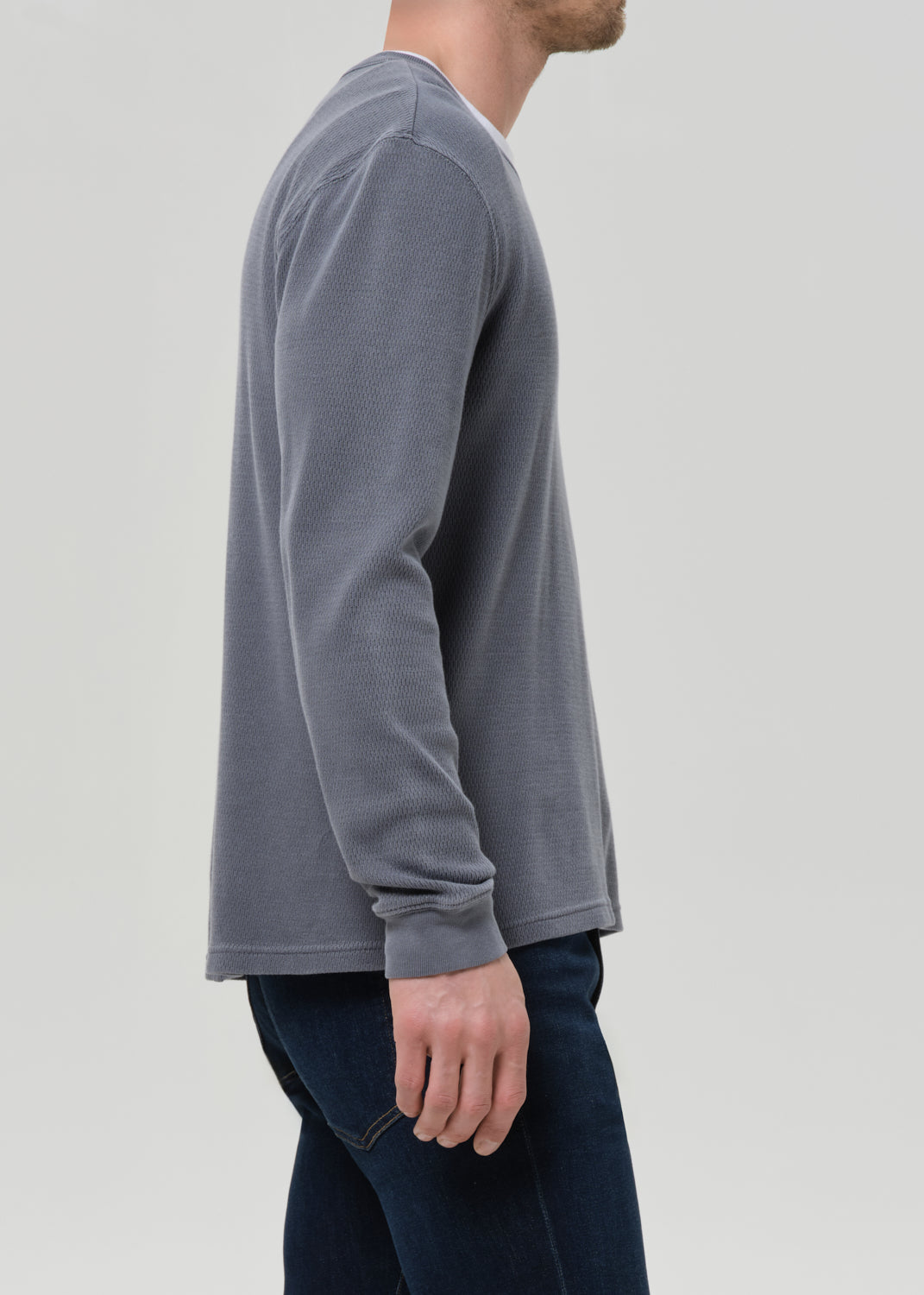 Person wearing a grey long-sleeve shirt on a light grey background