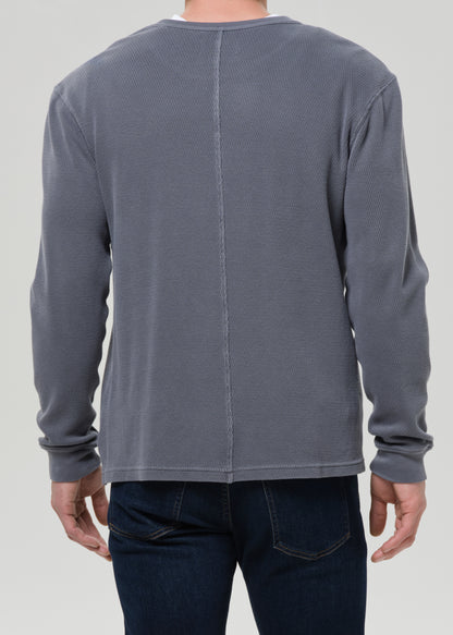 Grey long-sleeve shirt worn by a person on a grey background