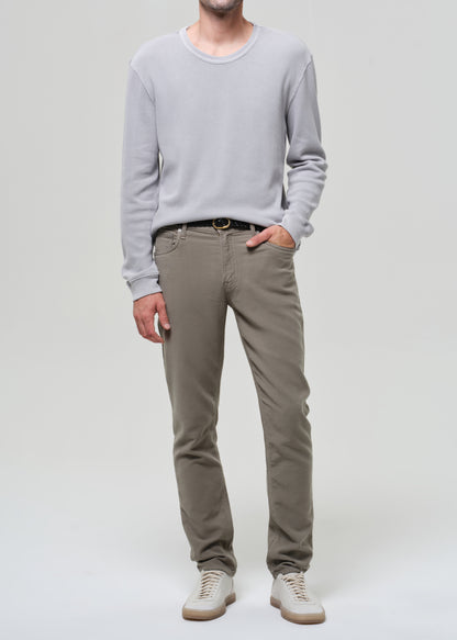 Person wearing a light gray sweater and beige pants on a white background