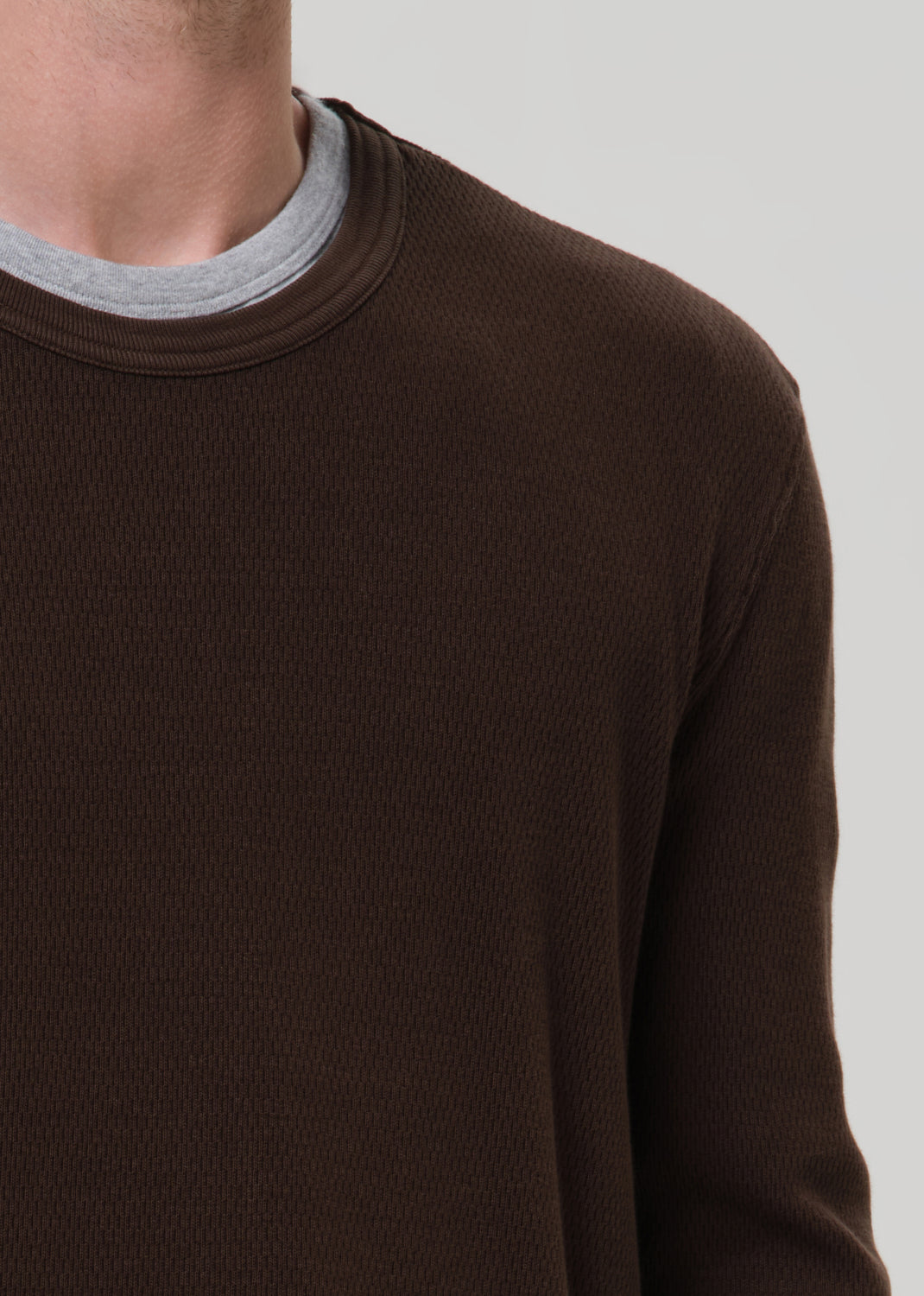 Brown long-sleeve shirt worn by a person on a grey background