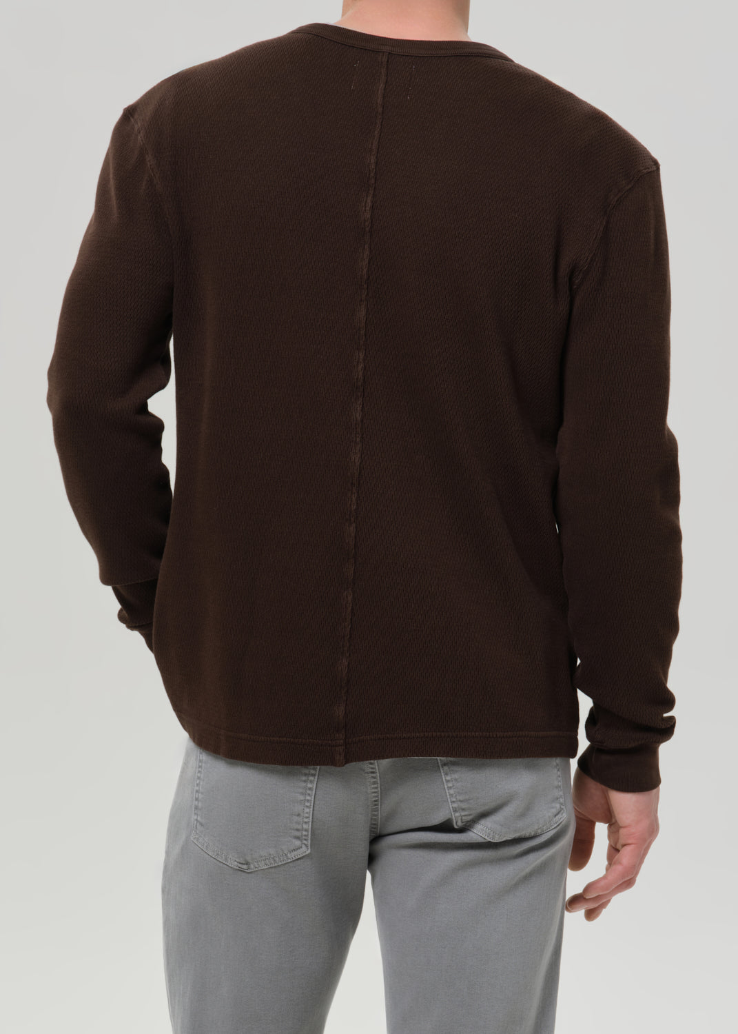 Person wearing a brown jacket on a grey background