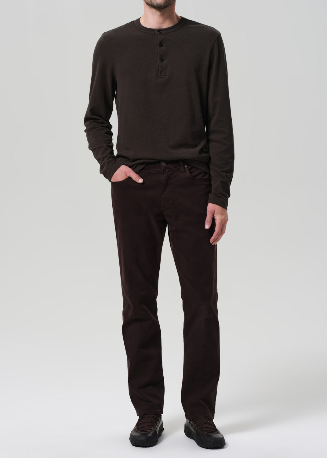 Person wearing a brown long-sleeve shirt and pants on a white background