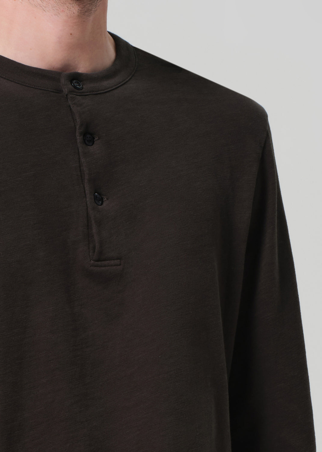 Close-up of a dark brown long-sleeve shirt with buttons.