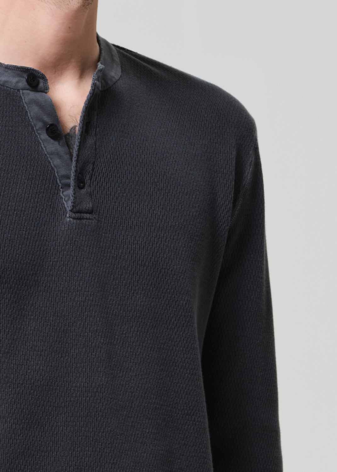 Black long-sleeve shirt with button details on a light gray background