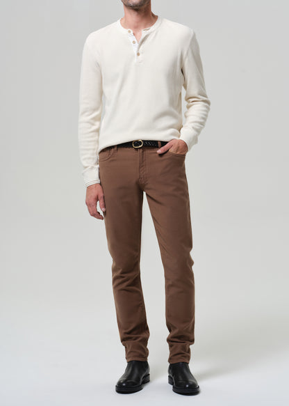 Man wearing a white sweater and brown pants on a plain background