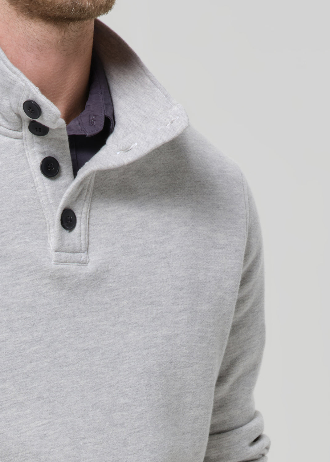 Close-up of a grey sweater with black buttons on a grey background