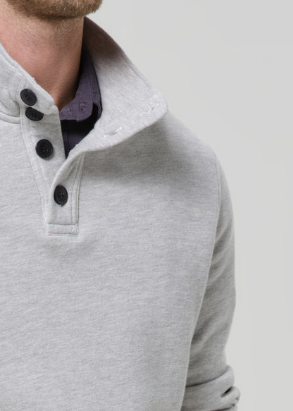 Close-up of a grey sweater with black buttons on a grey background