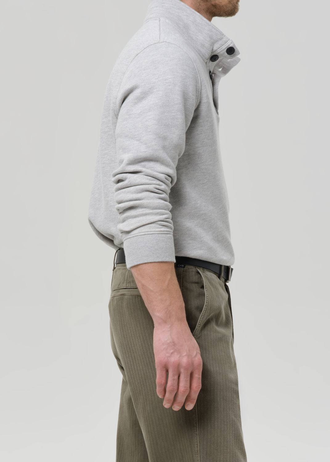 Person wearing a grey hoodie and green pants on a grey background