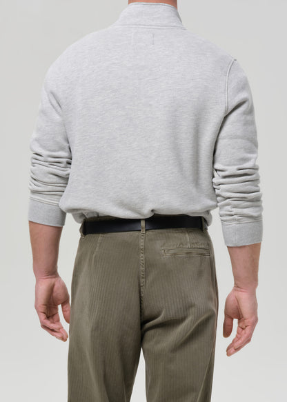 Person wearing a grey sweater and beige pants on a grey background