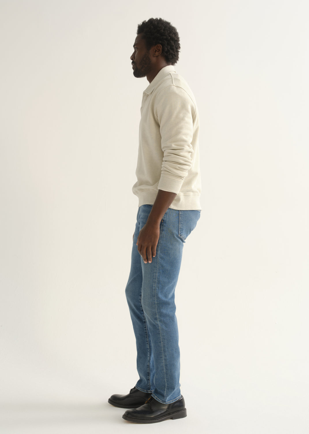 Person wearing cream rugby pullover and blue jeans back