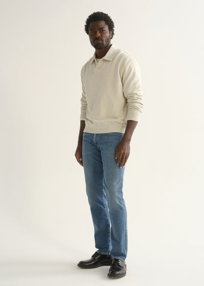 Person wearing cream rugby pullover and blue jeans front