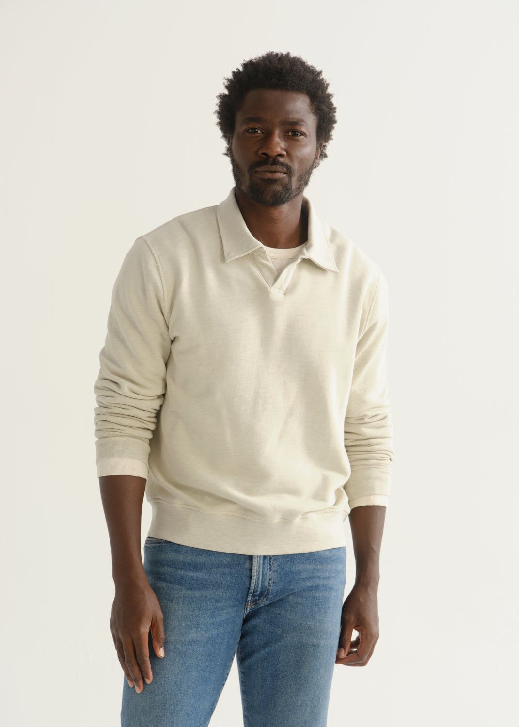 Person wearing cream rugby pullover and blue jeans front crop