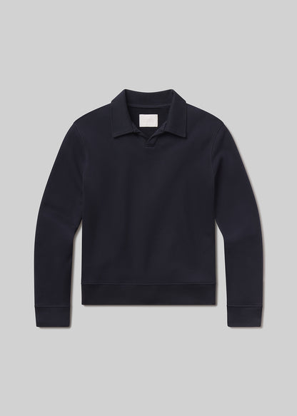 Flat lay shot of dark blue sweater with a collar on a grey background