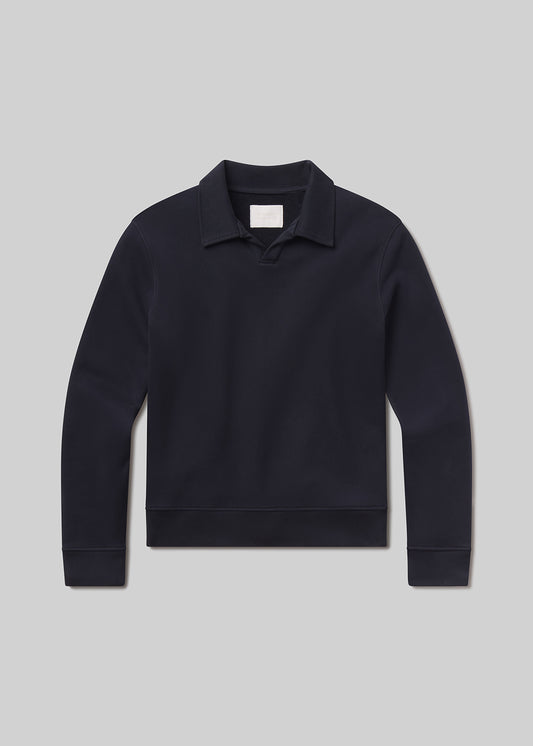 Flat lay shot of dark blue sweater with a collar on a grey background